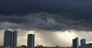 Prédios comerciais sob nuvens carregadas de temporal, com chuva se aproximando da cidade