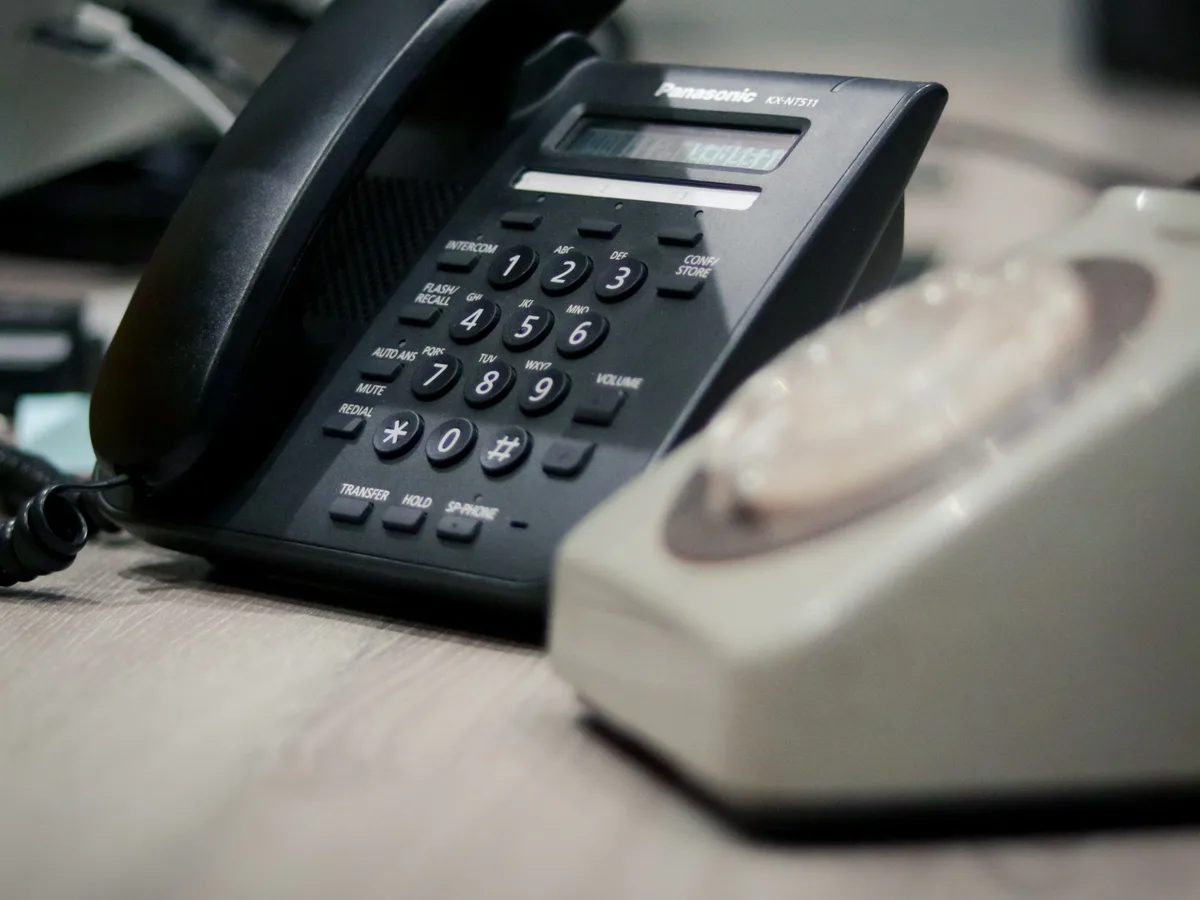 Telefone antigo de disco ao lado de um telefone de mesa moderno, mostrando a mudança da telefonia tradicional para a telefonia IP